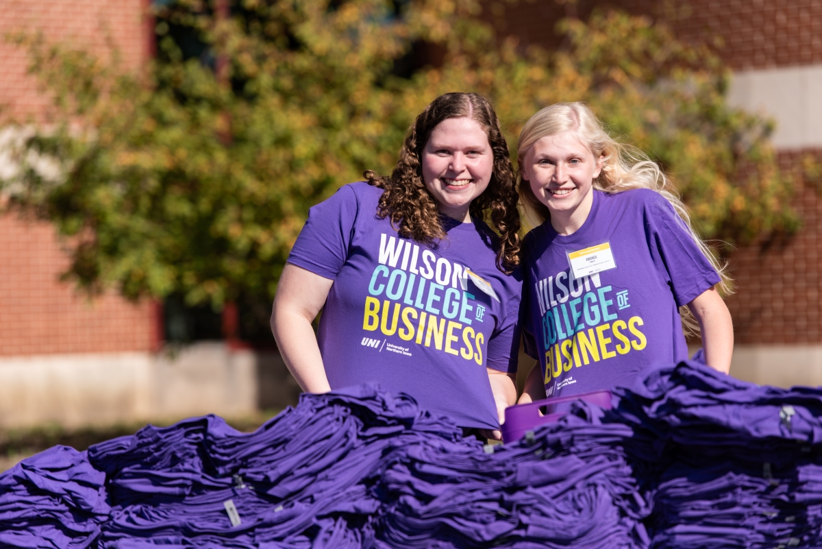 Two students wearing Wilson College of Business t-shirts passing out free t-shirts to students