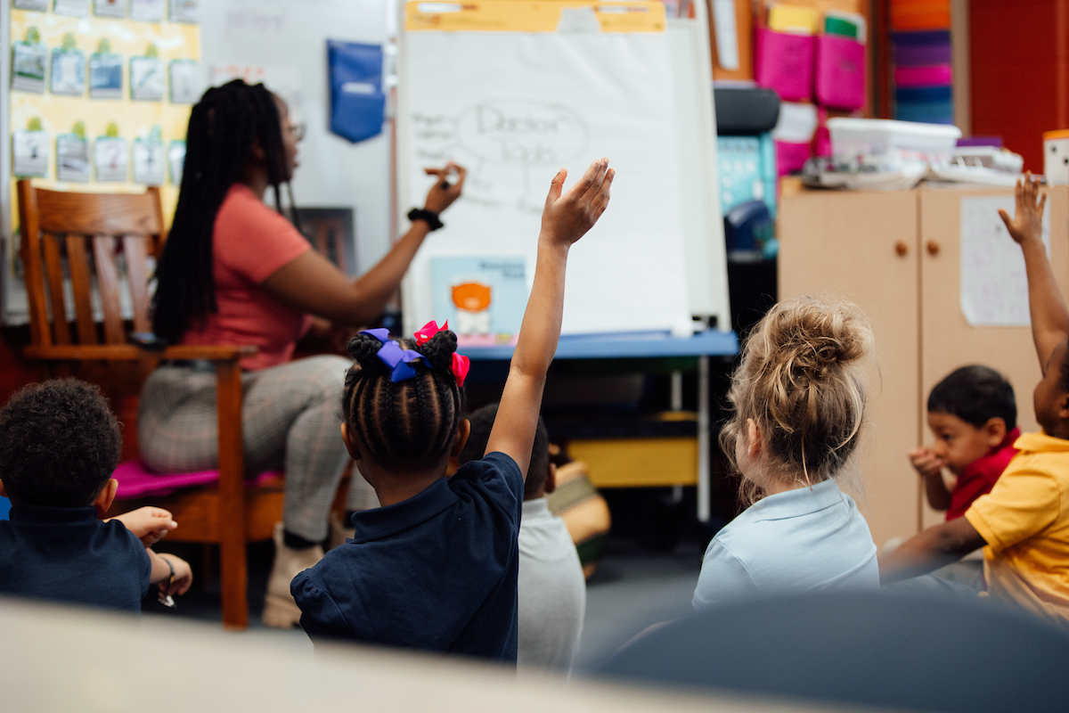 Teacher with students raising their hands