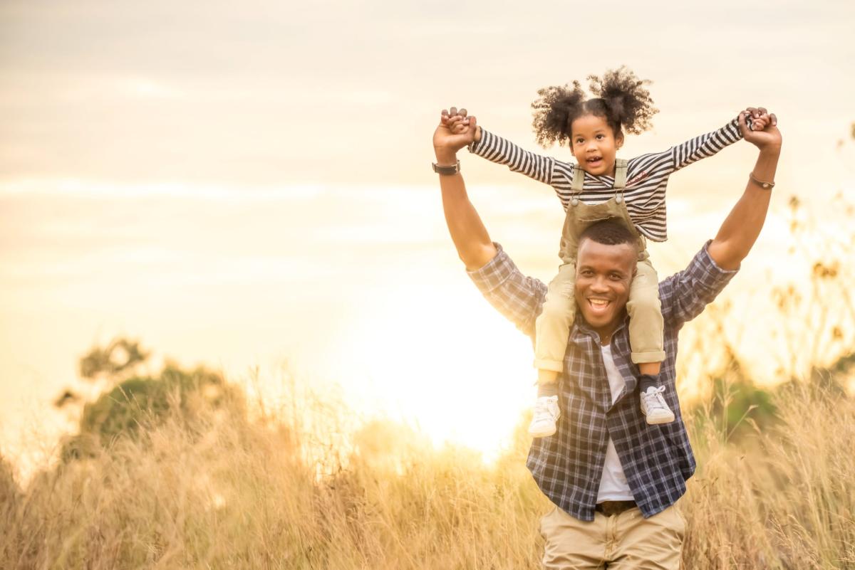 African American man carrying daughter on shoulders