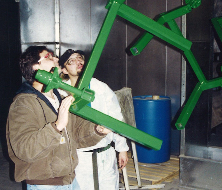 Two people holding a green spray coated piece of metal