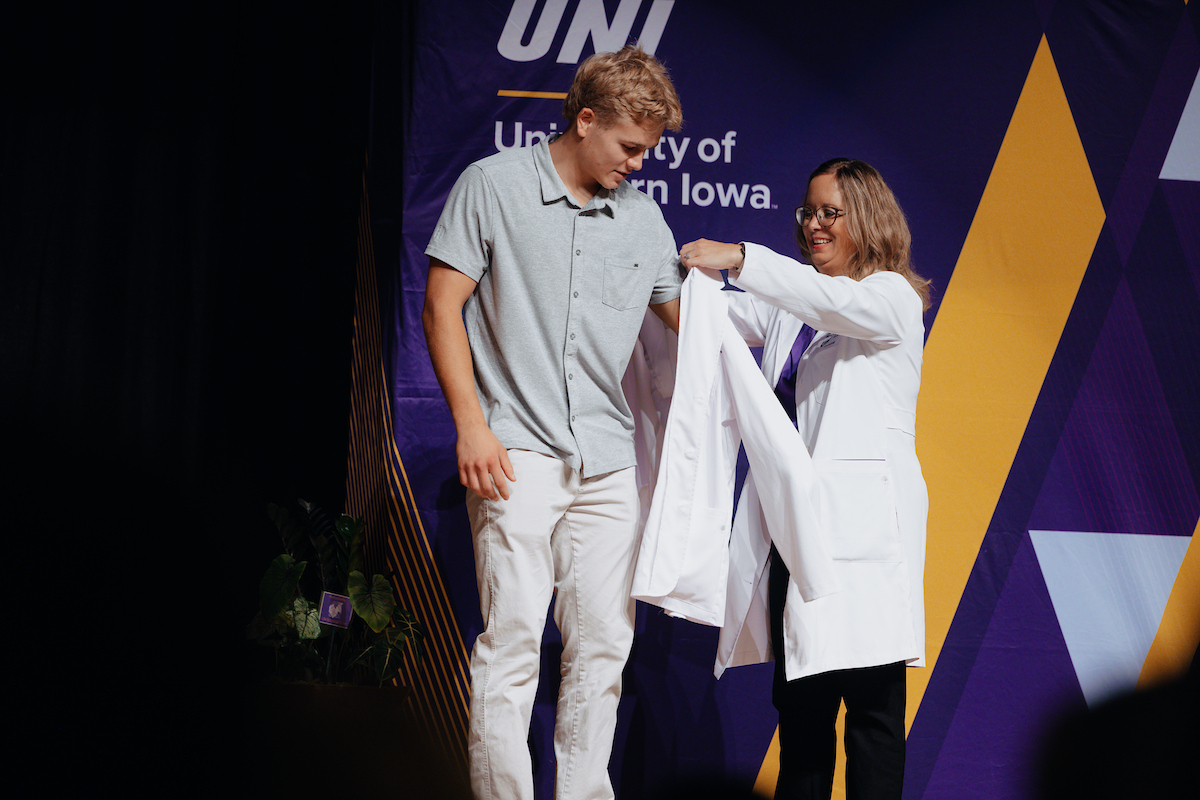 Nursing faculty member helps nursing student into their white coat