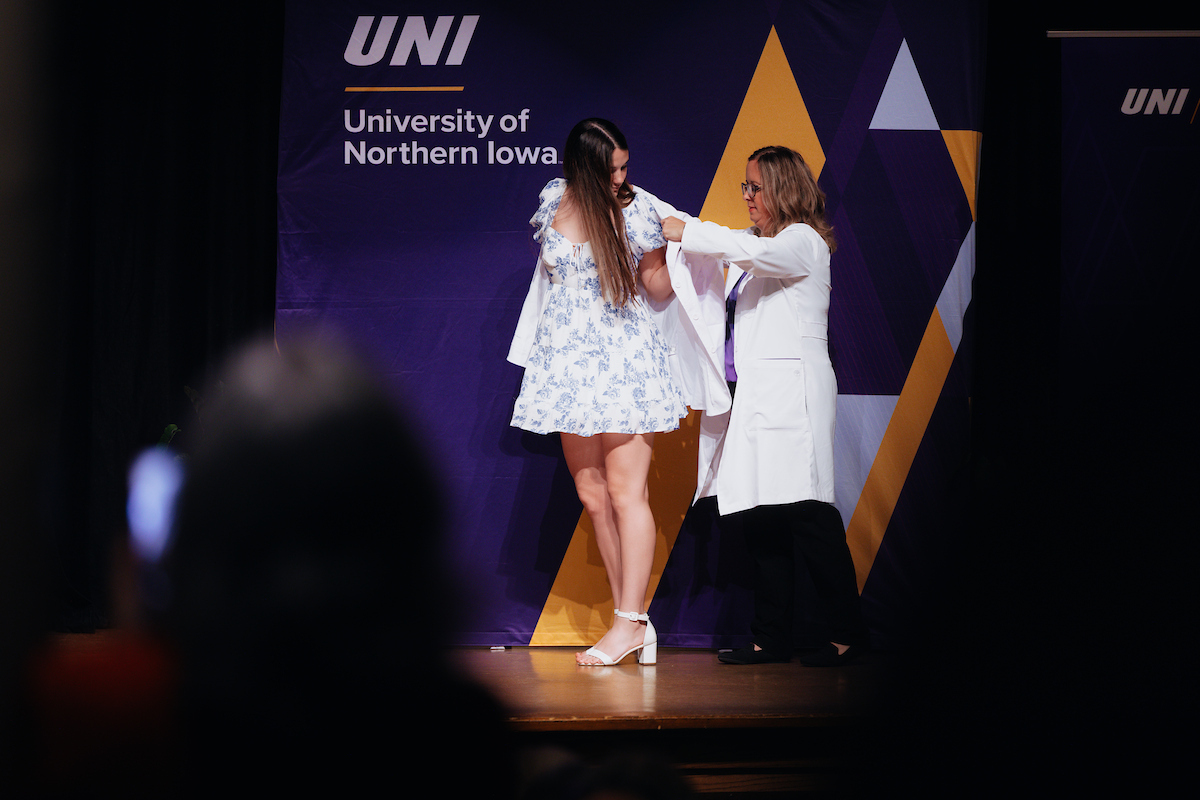 Nursing faculty member helps nursing student into their white coat