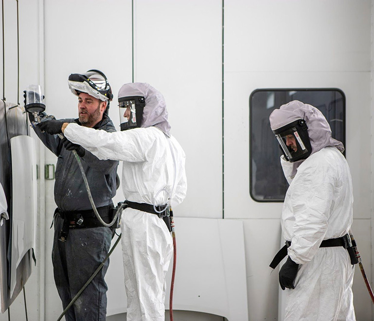 UNI students learning spray coating from instructor
