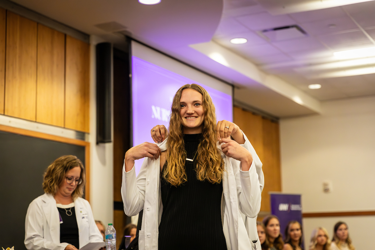 UNI BSN student putting on white coat