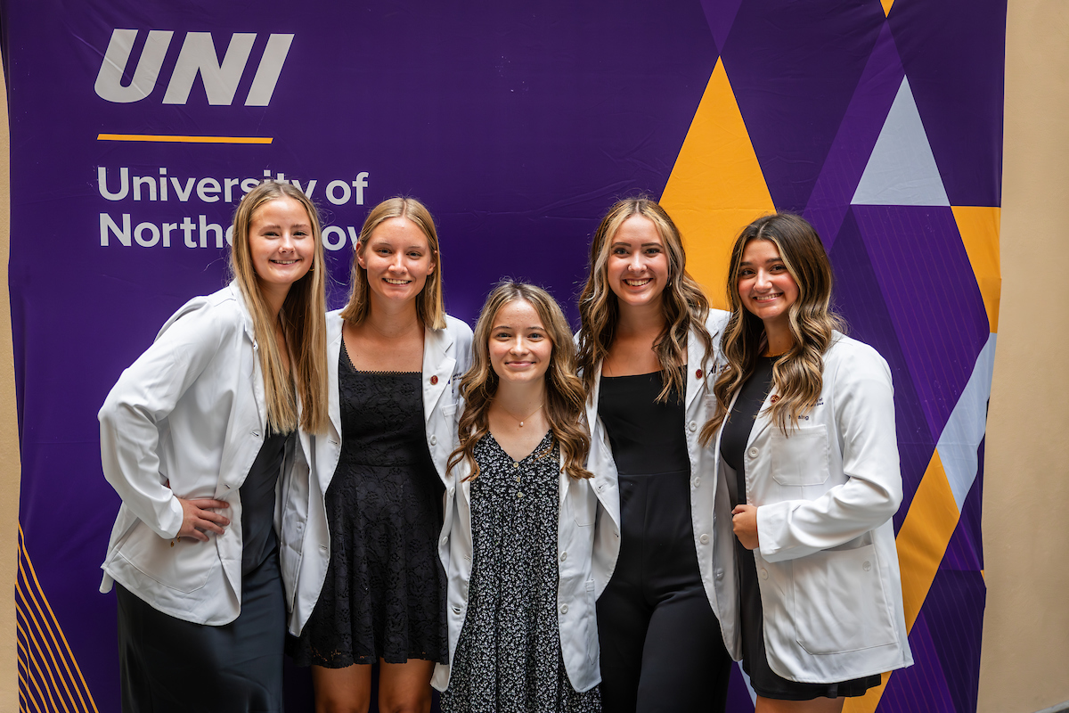 UNI students pose together wearing brand-new white coats