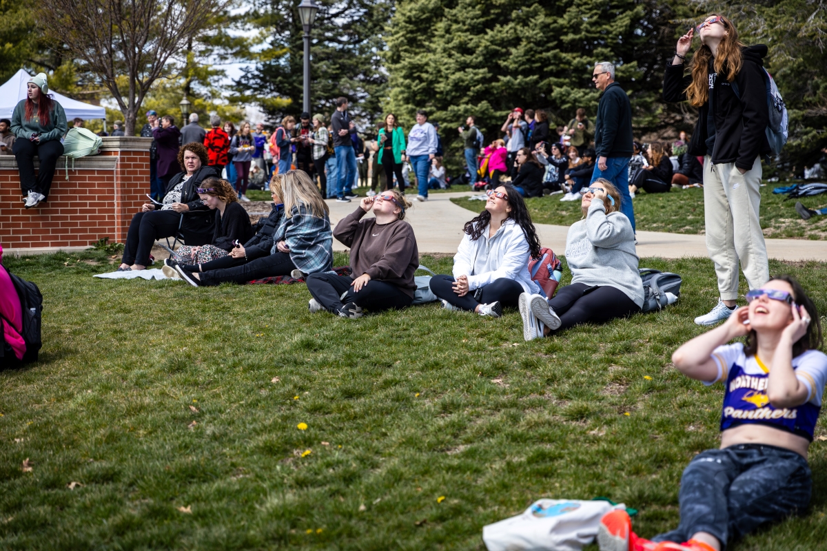 Students watch solar eclipse through eclipse viewing glasses on UNI campus