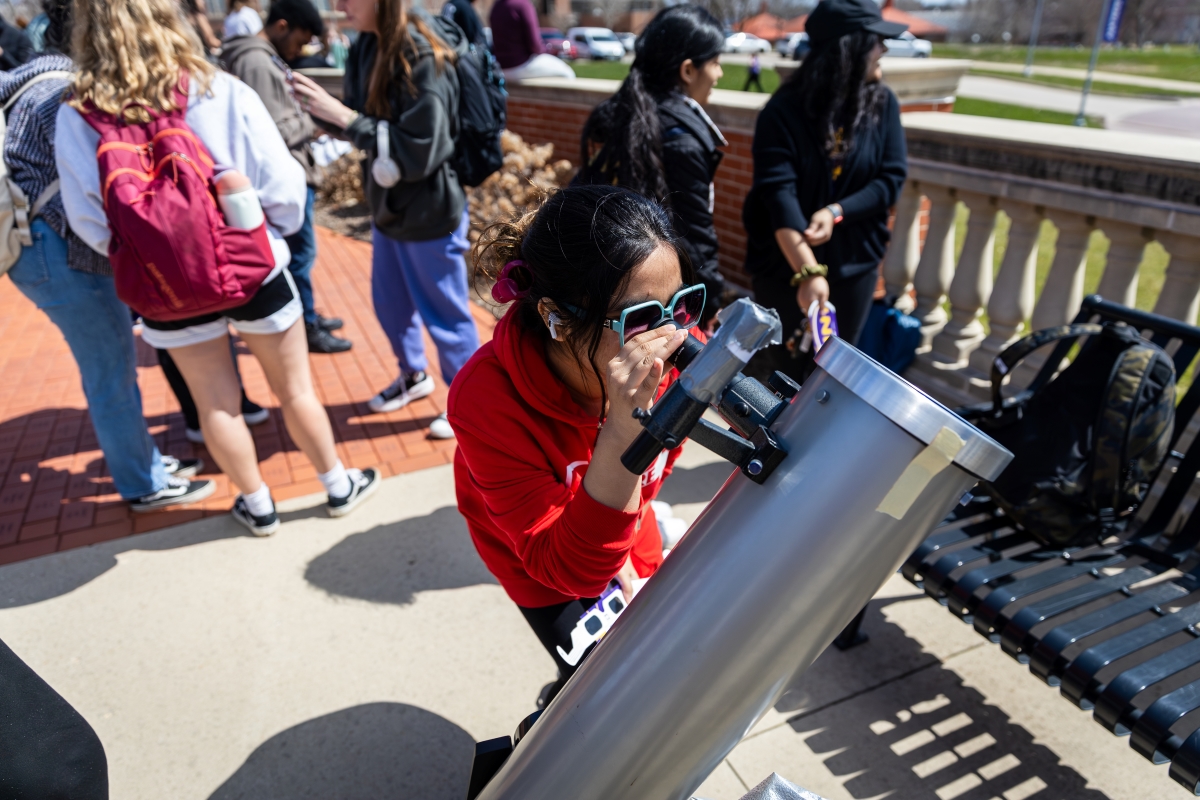 Student looks through telescope at solar eclipse