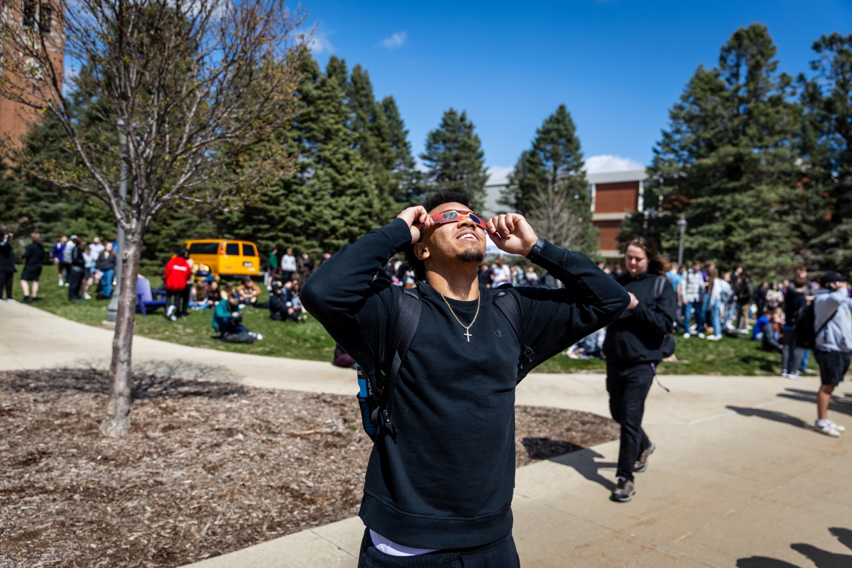 Student looks up at solar eclipse through eclipse viewing glasses