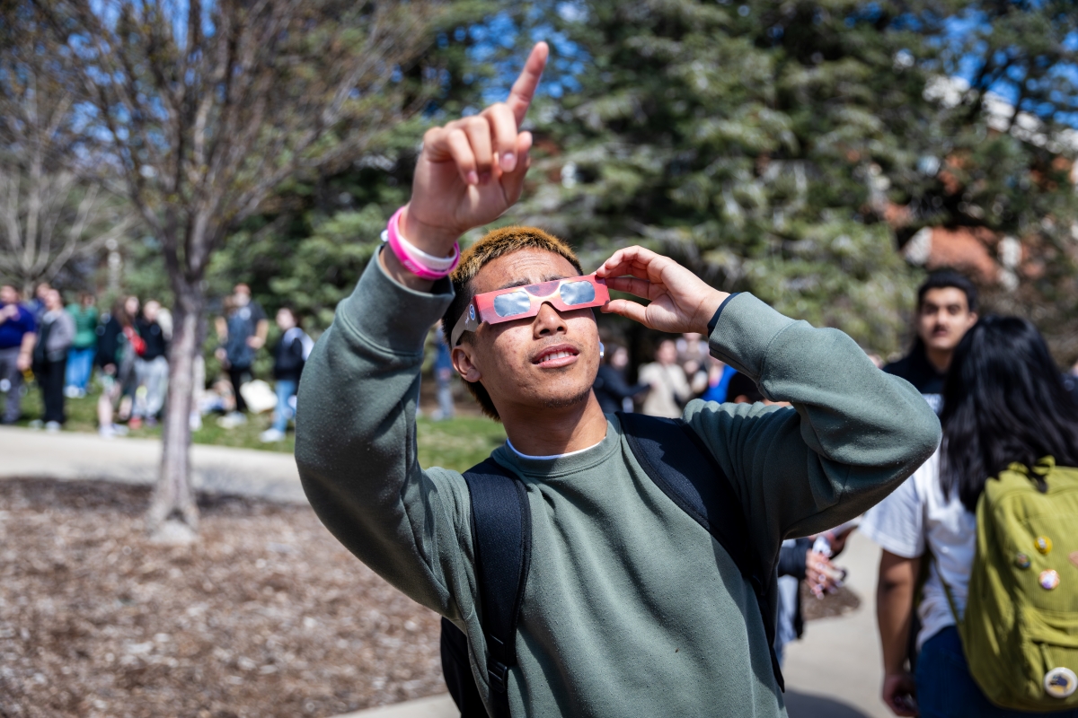 Student looks at solar eclipse through eclipse viewing glasses