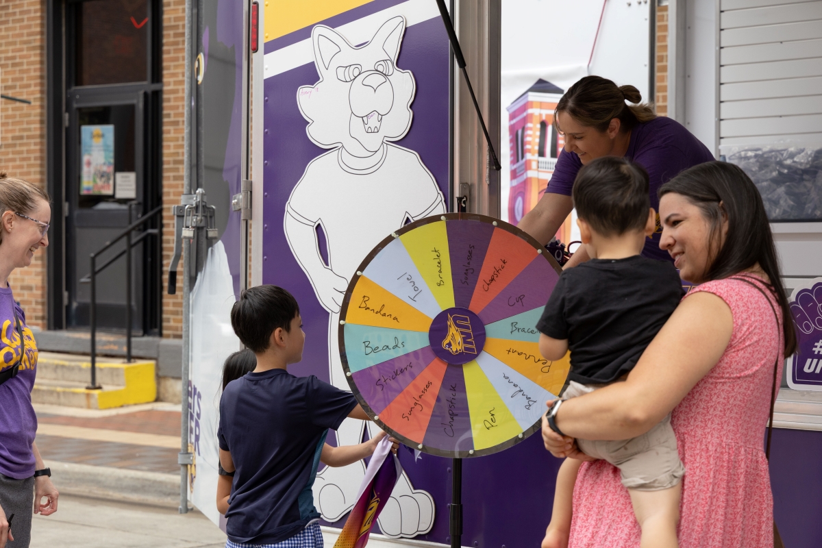 Children spin wheel for prize at UNI trailer in downtown Cedar Falls at RAGBRAI