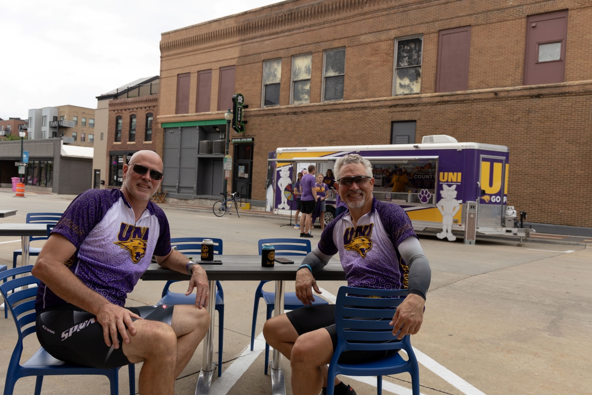 Two men wearing UNI jerseys sitting in downtown Cedar Falls