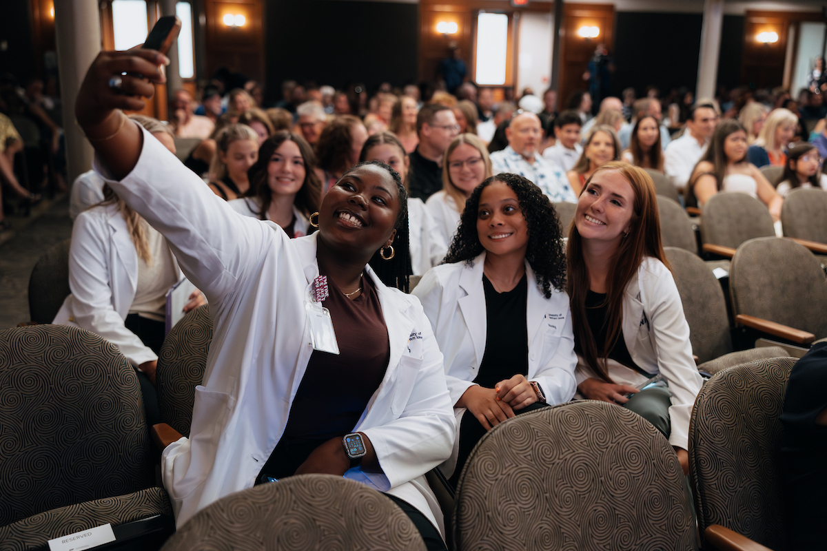 Nursing students take pictures in their white coats