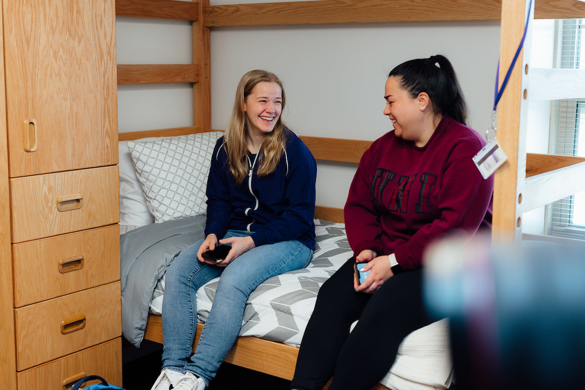 Two students sitting on a bed in the dorms