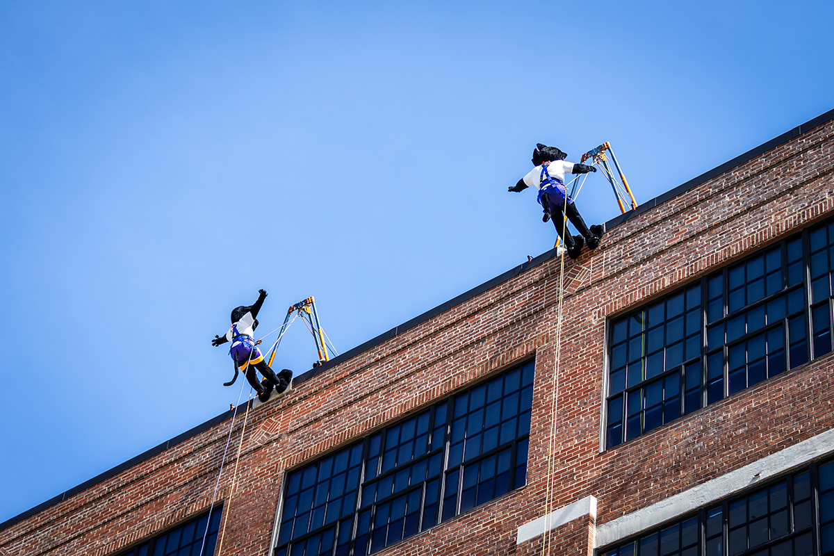 UNI mascots mid-jump from the edge of Techworks building. 