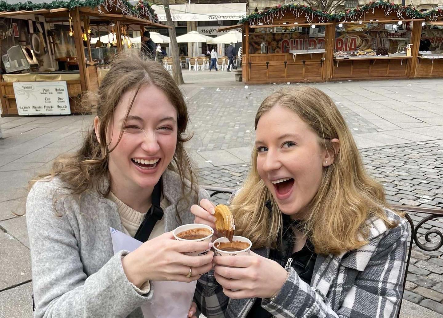 Two girls smiling and eating cookies.