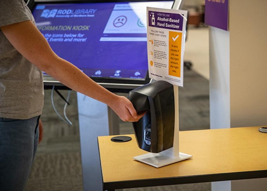 A student uses one of the many hand sanitizer stations spread across campus.