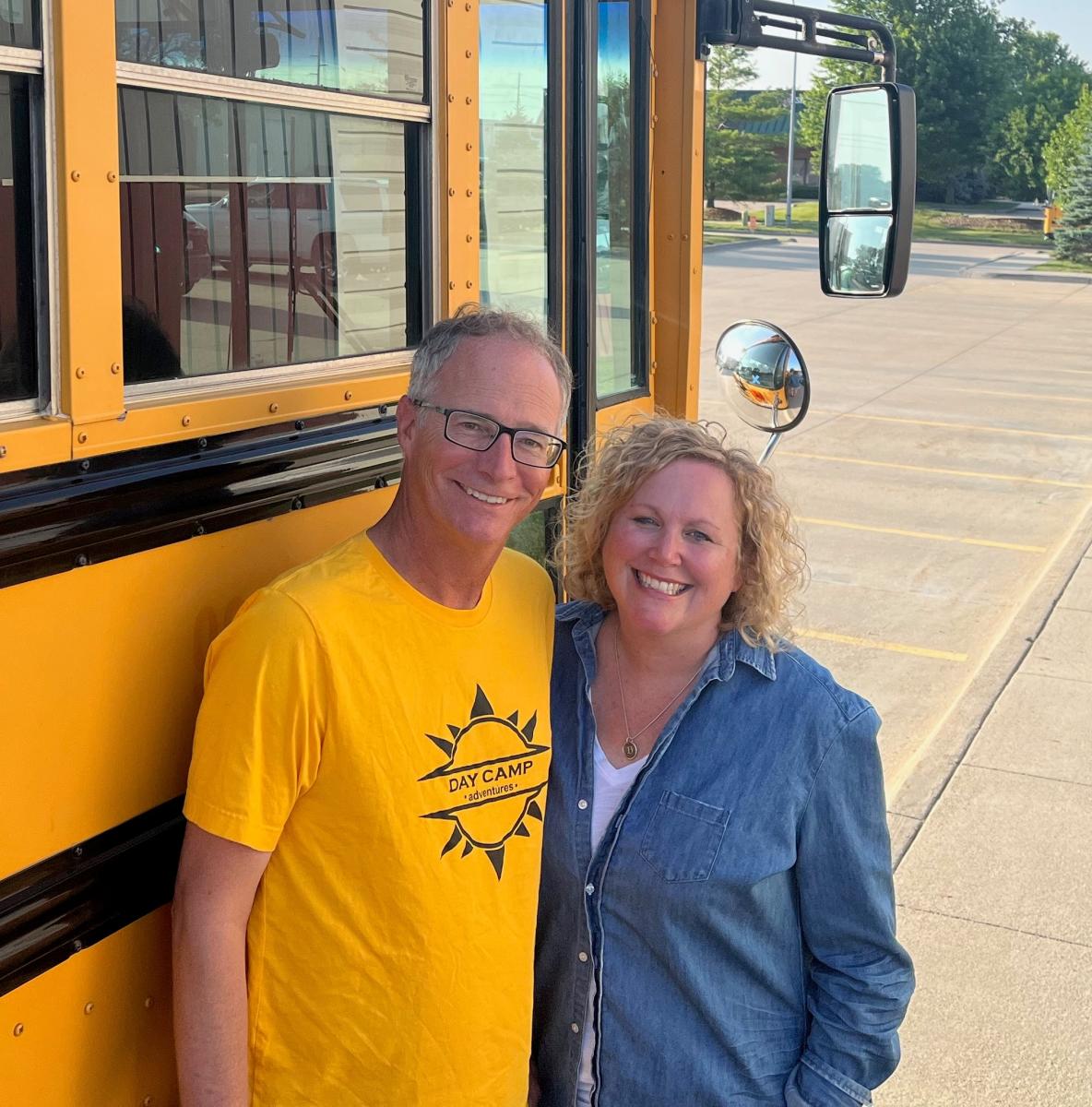 Adam and Darcy Nidey standing in front of a school bus