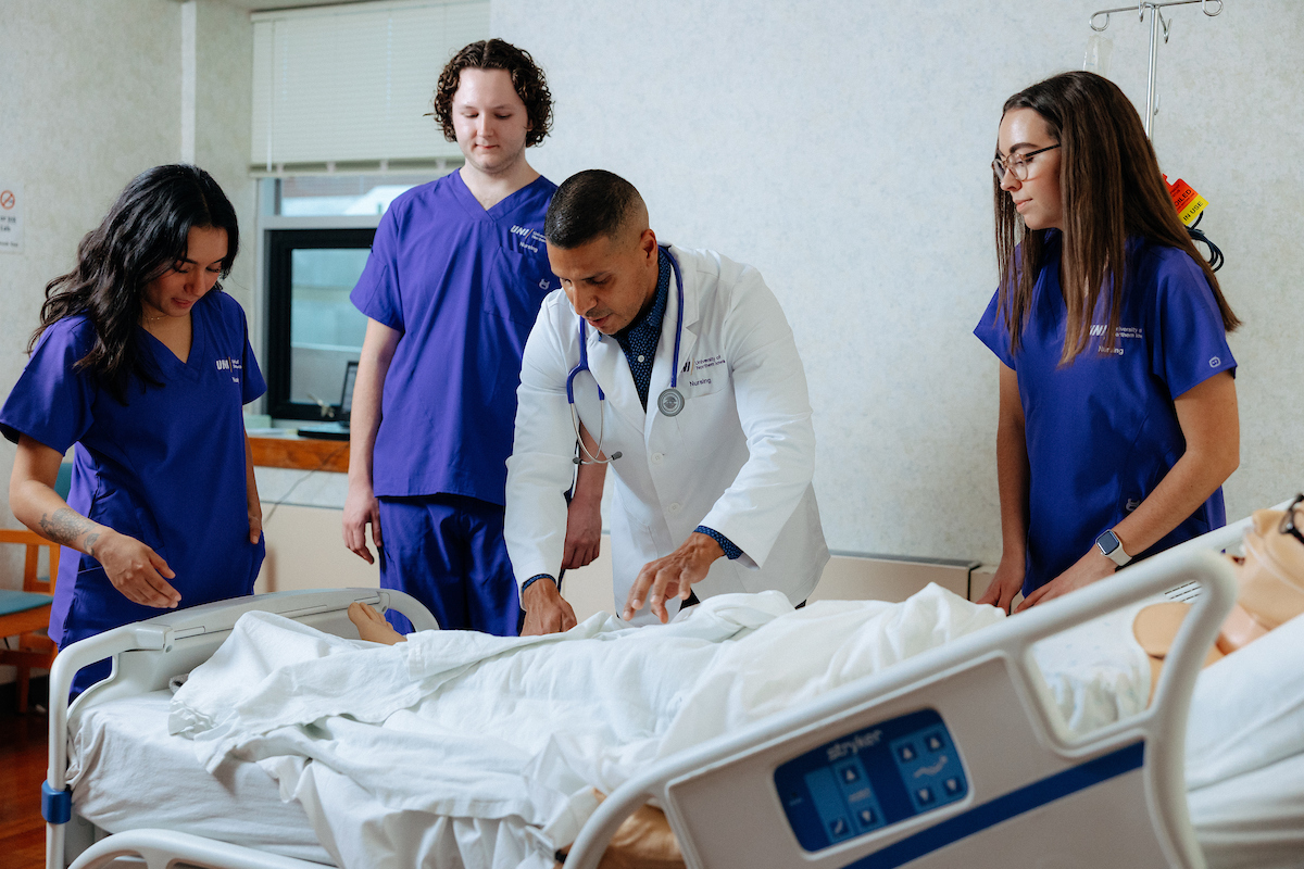 Jimmy Reyes working with UNI nursing students in simulated hospital setting