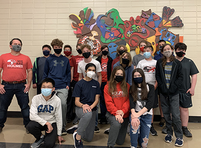 Students from Holmes Junior High School pose with a piece of art they created with the help of UNI art education students.