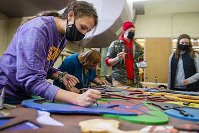UNI students work on a piece of art they created with students from Holmes Junior High School.