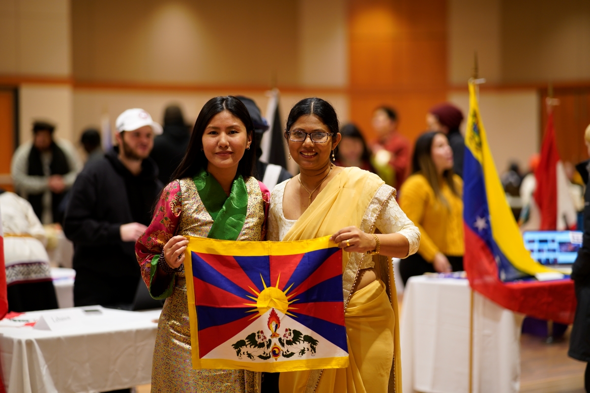 Two students dressed in traditional clothing, holding scarf