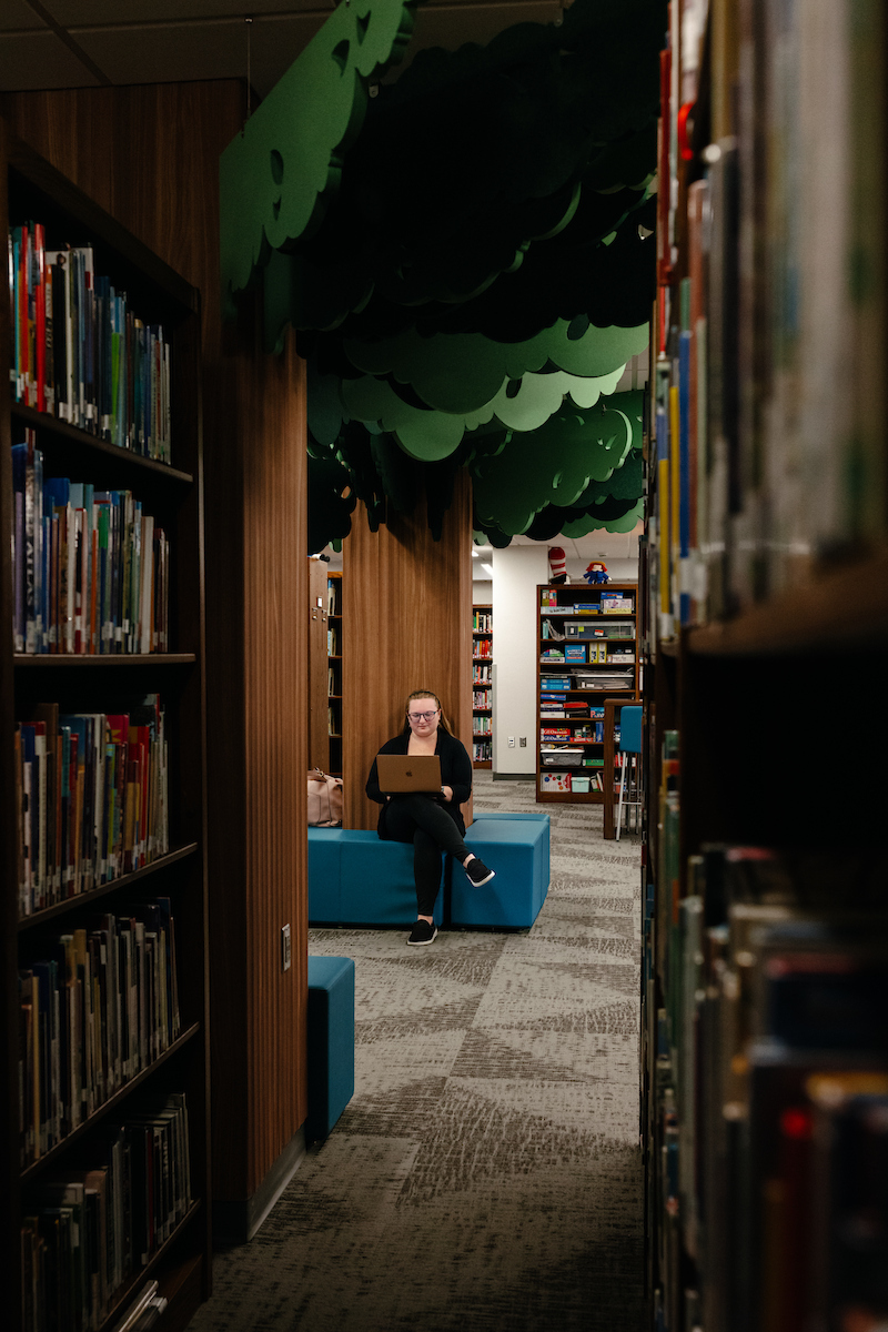 Student studying in TEACH Studio while sitting under a fabric-and-wood tree