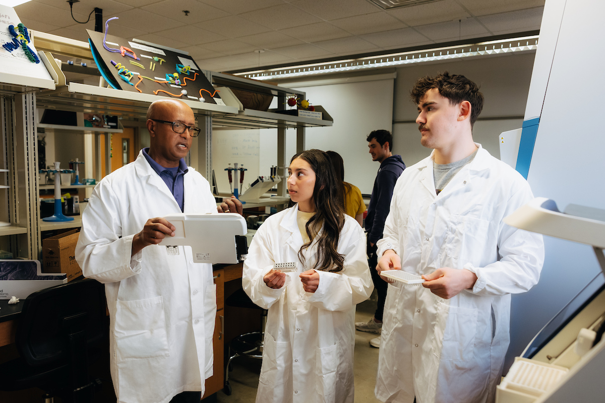 Biology students working with professor in lab