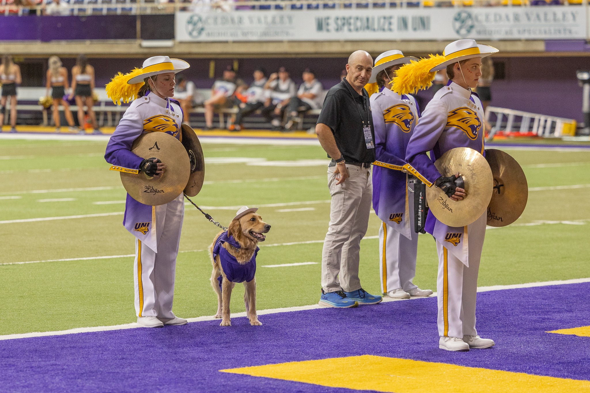 Panther Marching Band performing in the UNI-Dome with Winnie the service dog by Gabi Riessen's side