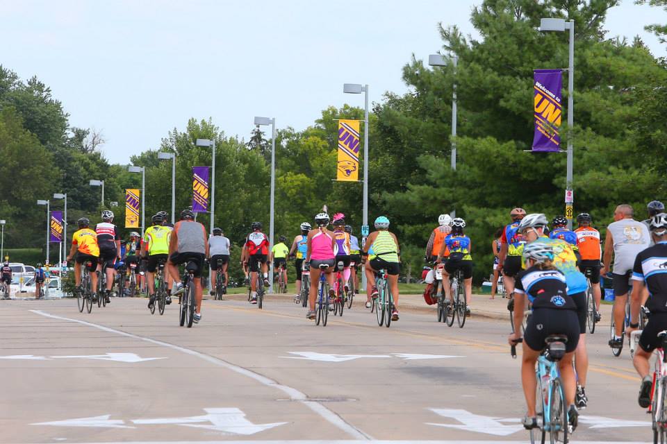 RAGBRAI riders ride through Cedar Falls with UNI banners