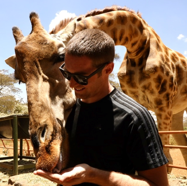 Brett Meehan feeding a giraffe out of the palm of his hand