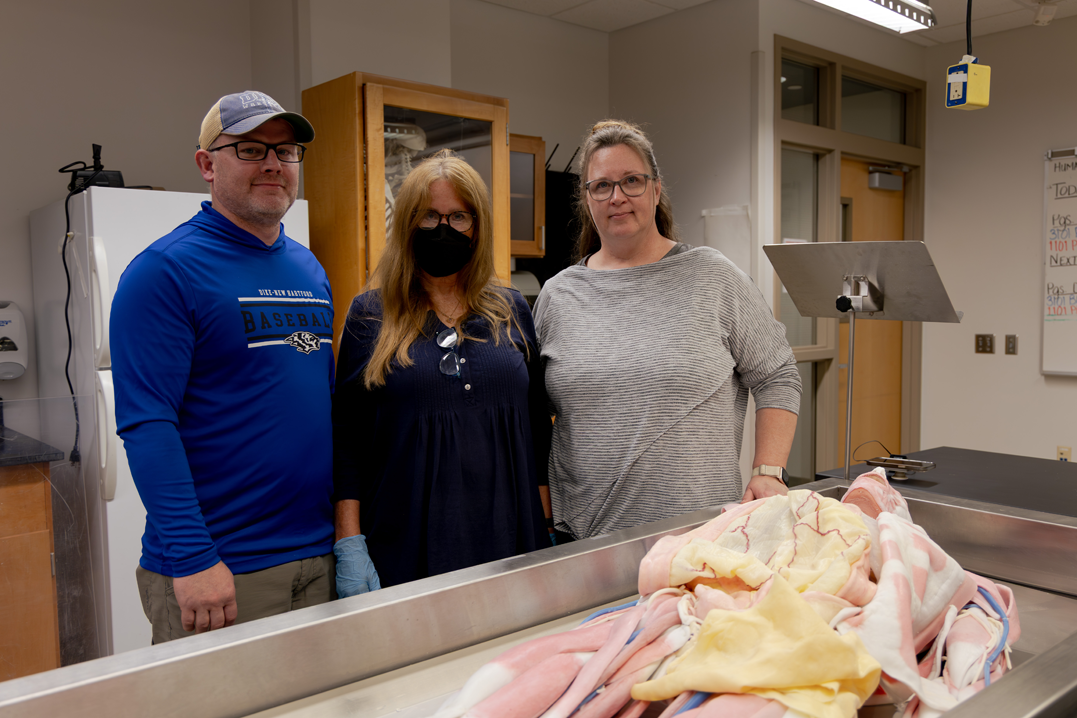 Anatomy and physiology professors at UNI standing next to the synthetic cadaver.