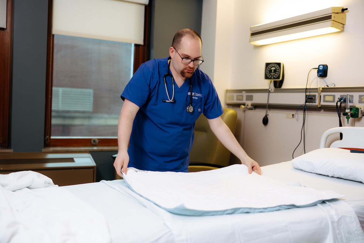 Nursing student changing bed sheets
