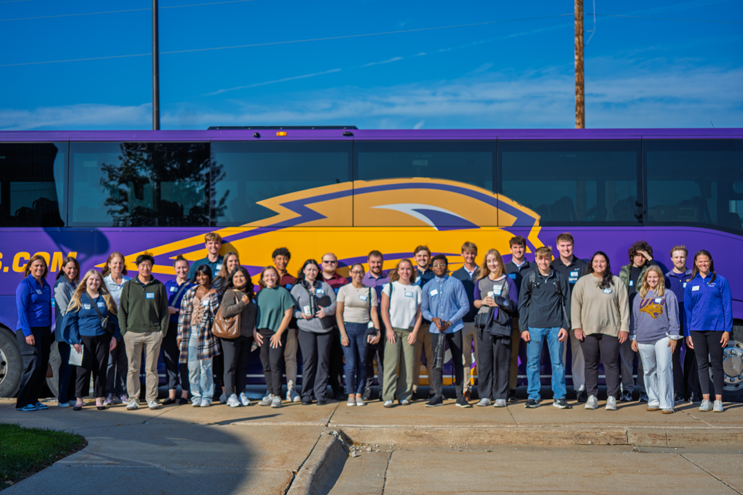 Students who attended the Wilson in the Valley event stand in front of UNI bus for a picture.