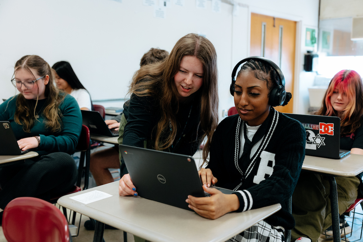 Teacher education student helping one of her students at their desk