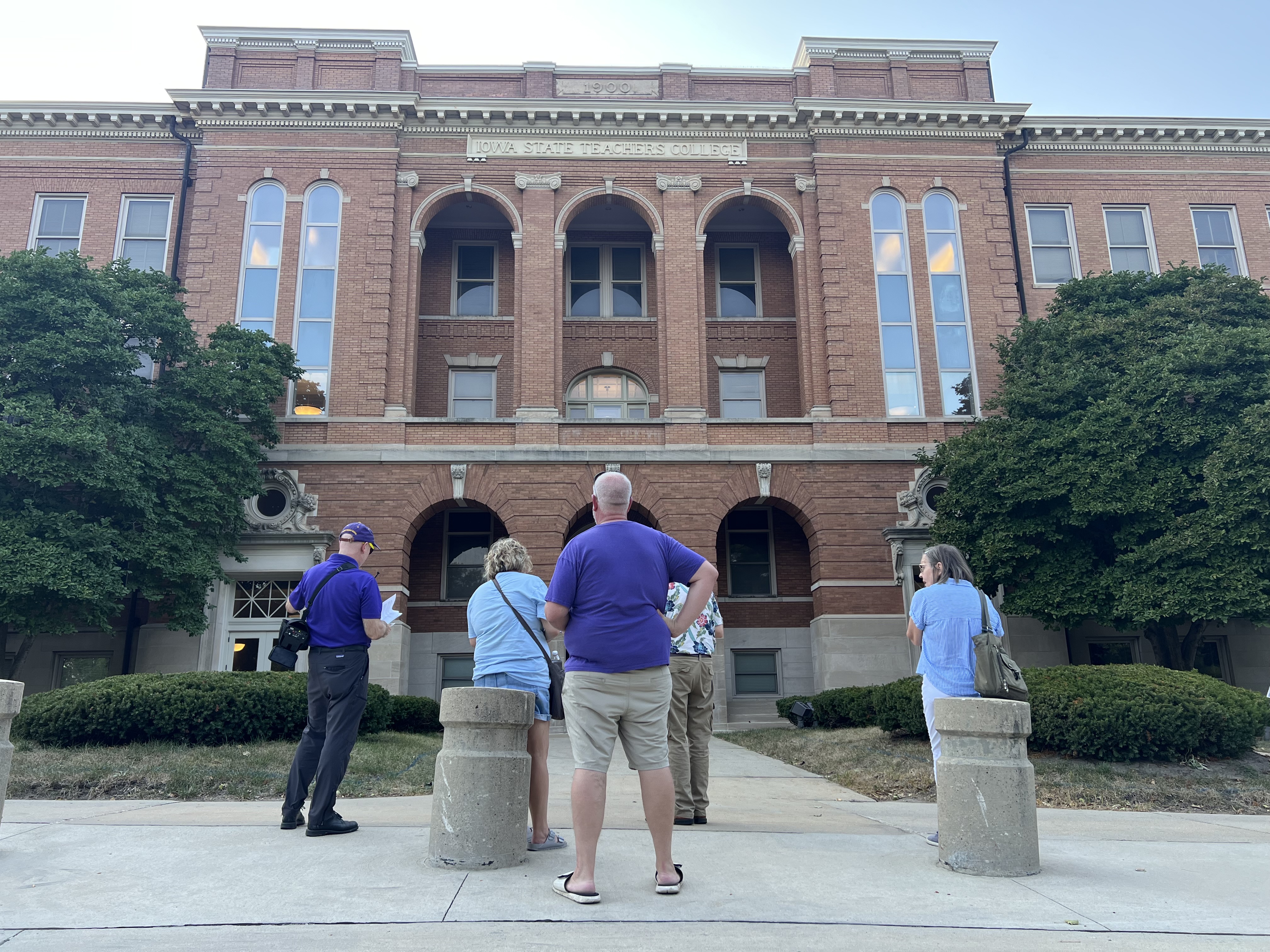 Walking tour participants stand outside Lang Hall to learn about its history.