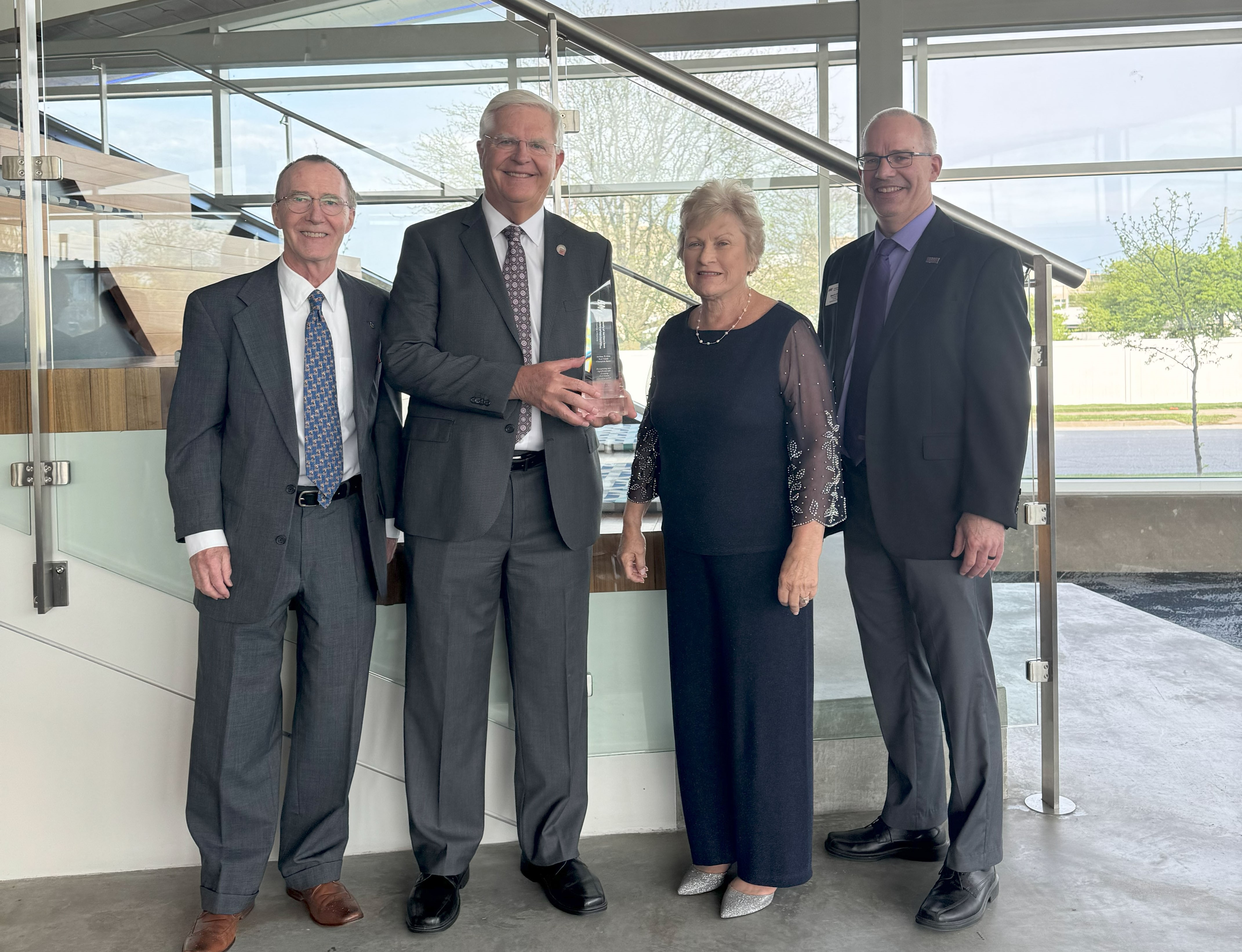 Tom Nordstrom holding his award, alongside his wife, Art Cox and Brett Olsen