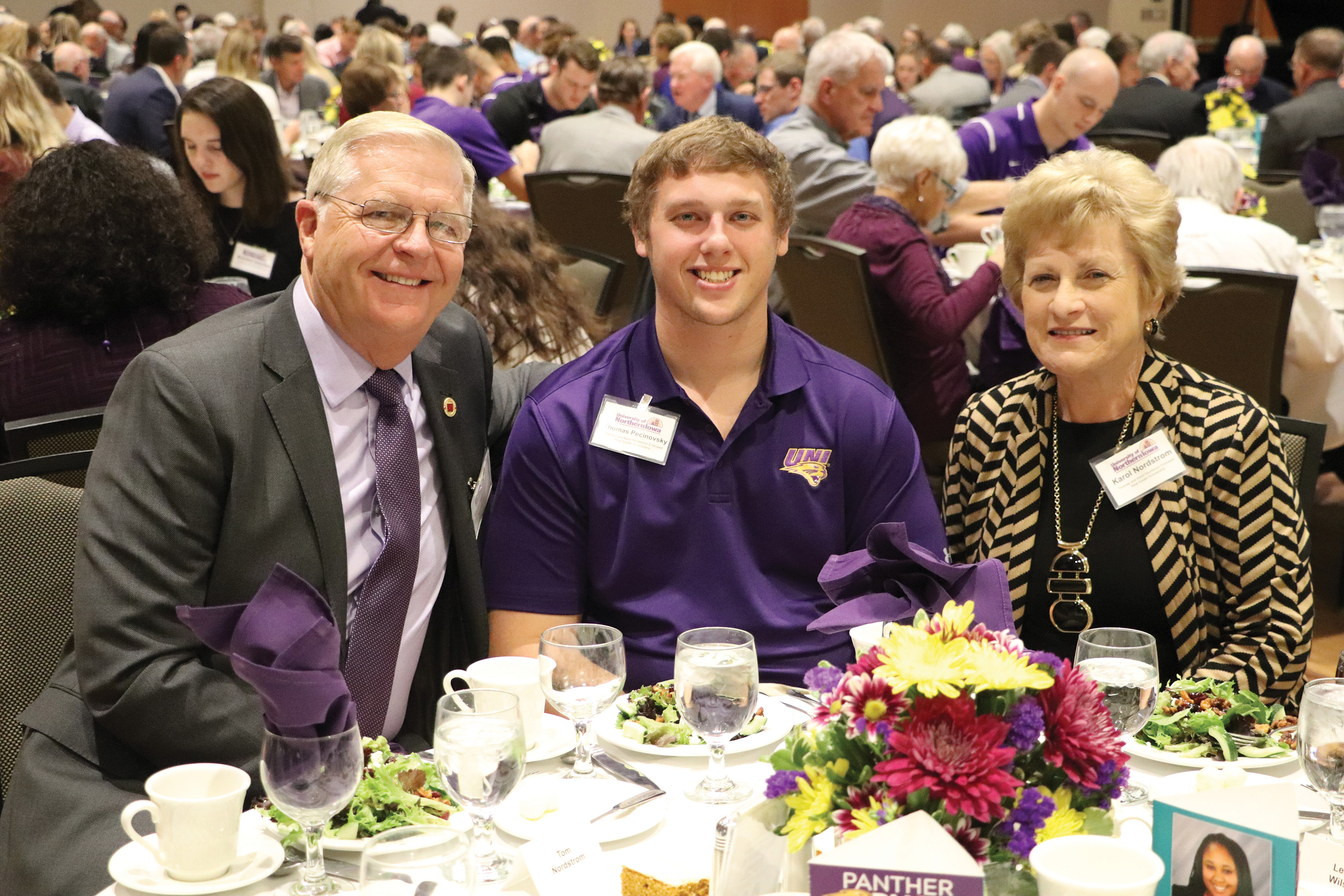 Tom and Karol Nordstrom sit with a UNI student at the UNI Scholarship Luncheon