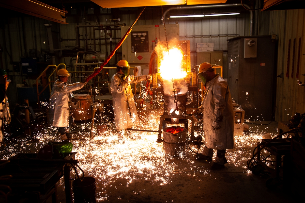 People in protective gear casting metal