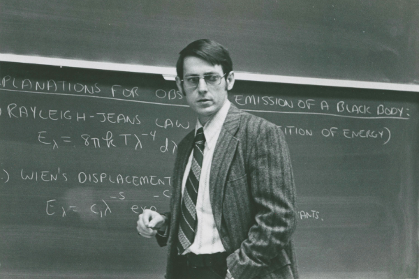 1978-03-27, Paul Rider teaching in front of a blackboard with formulas for explanations of a black body written on it.