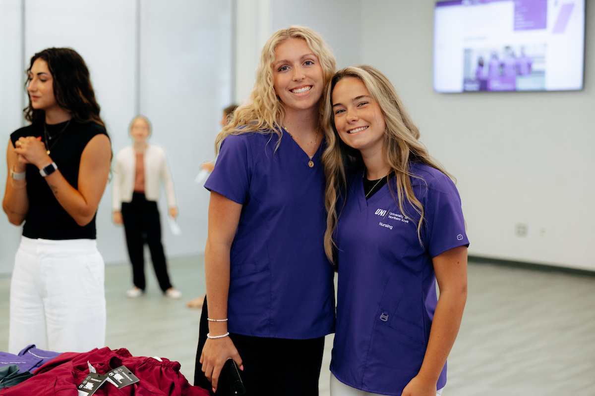 Two UNI nursing students wearing purple scrubs