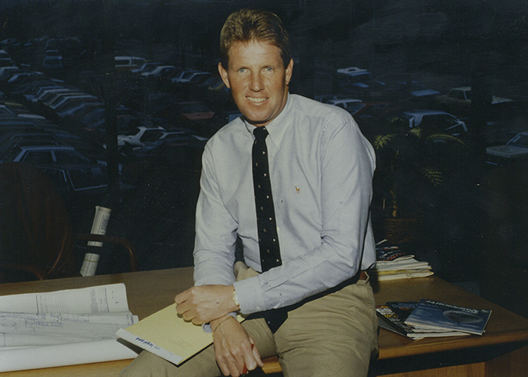 A young David Wilson sitting on a desk overlooking a car dealership