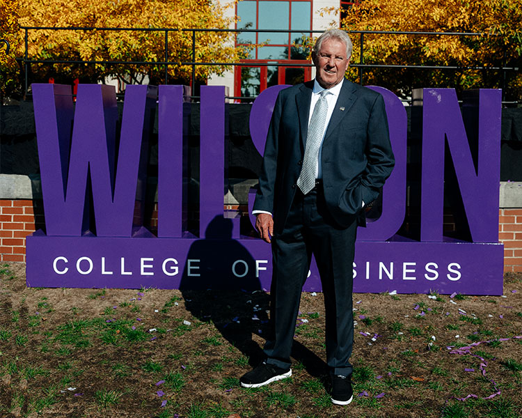 David Wilson standing in front of the Wilson College of Business sign