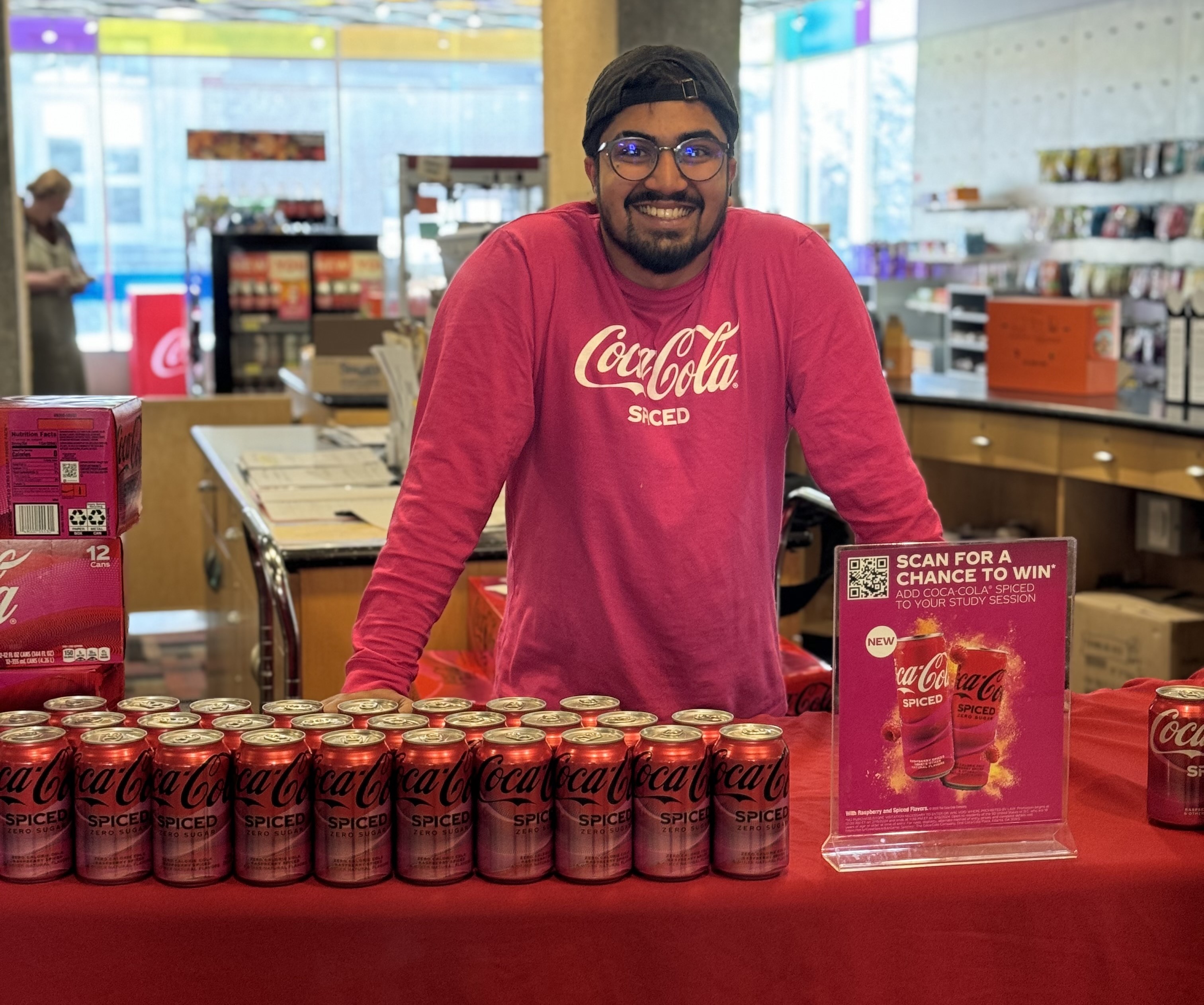 Gavik Kuruppu with cans of Coca-Cola Spiced at Essentials on UNI campus