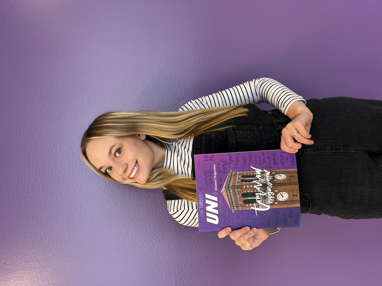 Kaina Geetings poses with Alumni Magazine with cover using her custom font