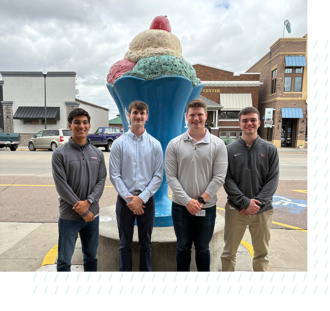 Mitchell Augustin stands with coworkers in front of ice cream sculpture