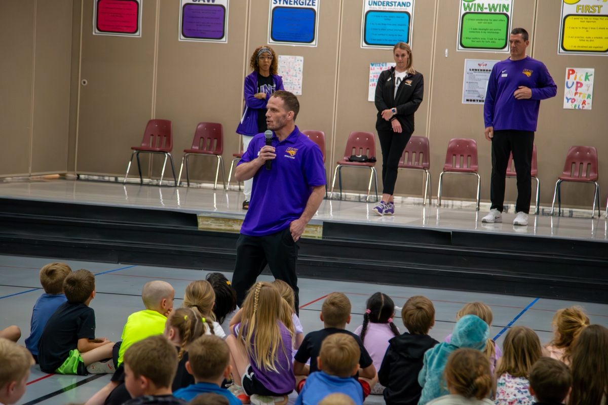 Coach Doug Schwab speaking in front of elementary school students