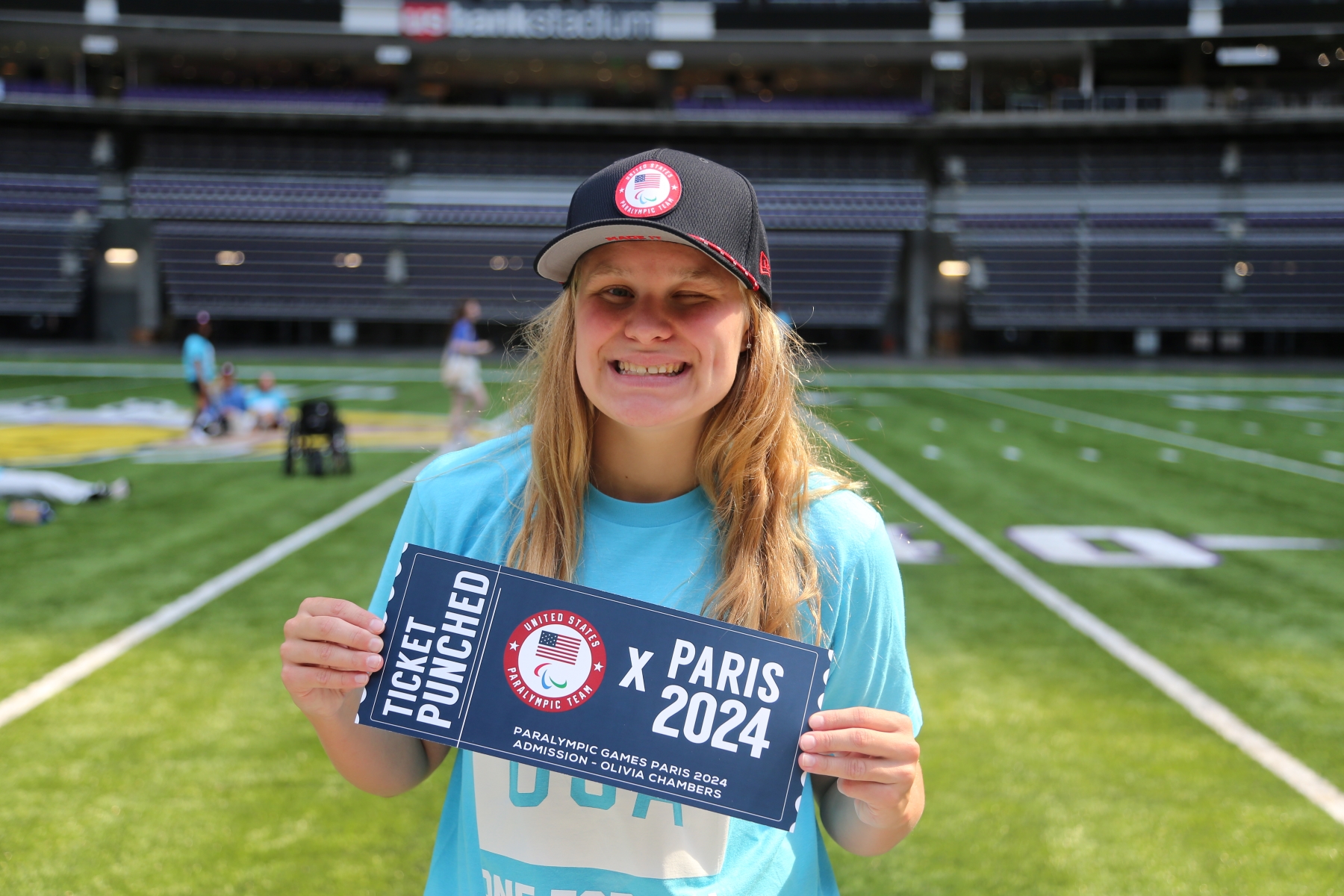 Olivia Chambers holding sign that says "Ticket Punched: Paris 2024"
