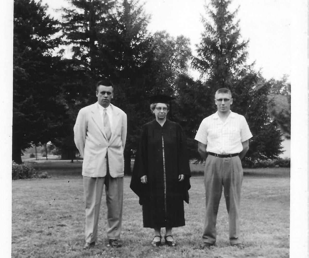 Mervil Adams-Boeck in graduation attire with two adult sons