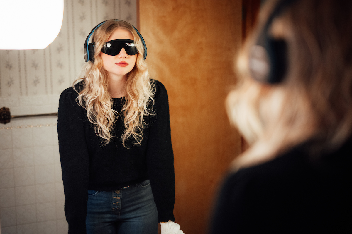 Dementia simulation participant wearing glasses and headphones looking in mirror