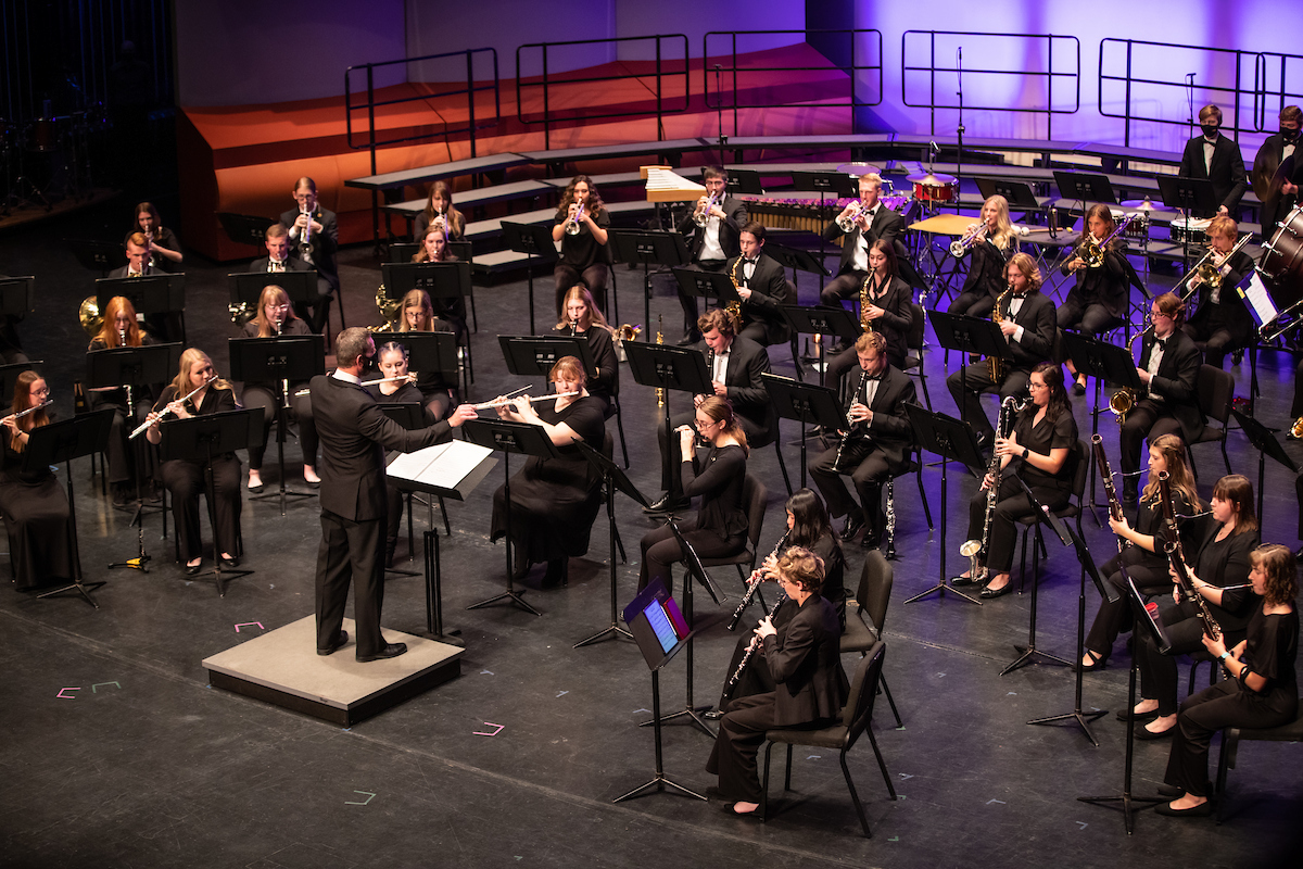 Musicians playing instruments on stage with conductor